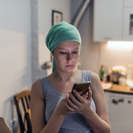 vrouw met smartphone met sjaaltje chemotherapie