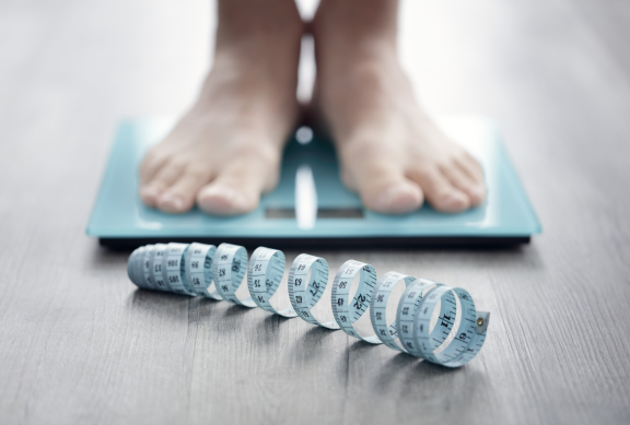 Persoon op weegschaal en lintmeter - iStockphoto