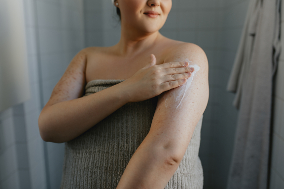 Lichaamsverzorging. Vrouw brengt crème aan na het douchen