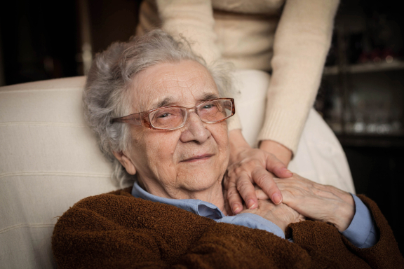 Oudere vrouw thuis houdt handen vast van mantelzorger
